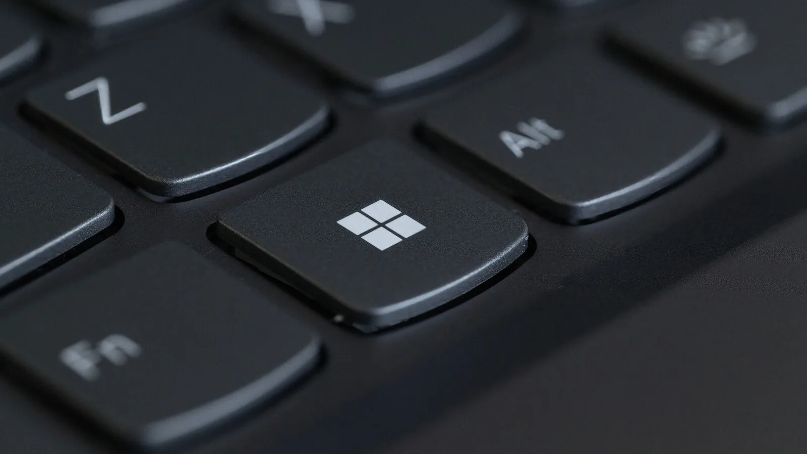 Teclado de portátil preto visto de muito perto, com a tecla Windows em destaque entre as teclas Fn e Alt