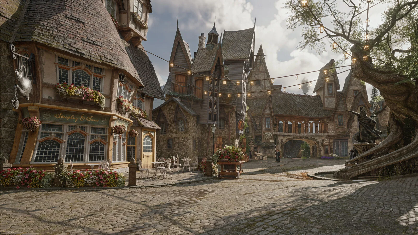 Praça empedrada de uma vila em Hogwarts Legacy, com casas de telhados inclinados, flores nas janelas, luzes penduradas e uma árvore retorcida à direita