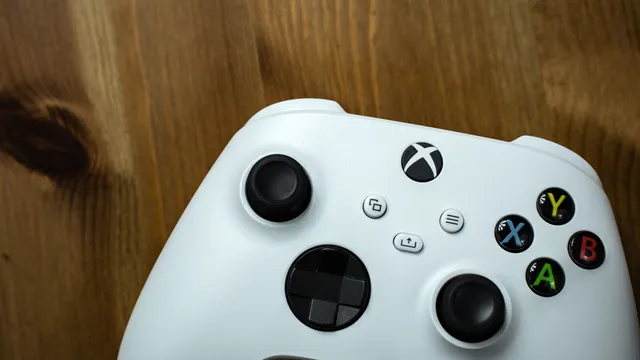 Comando branco da Xbox, com os botões A, B, X e Y coloridos, pousado sobre uma superfície de madeira