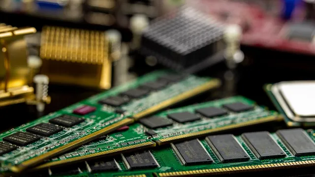 Módulos de memória RAM verdes e processadores pousados sobre uma placa de computador