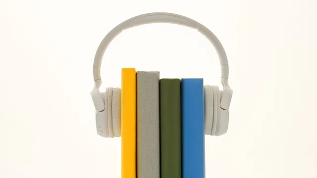 Auscultadores brancos a envolver quatro livros de lombadas coloridas, em pé sobre fundo branco