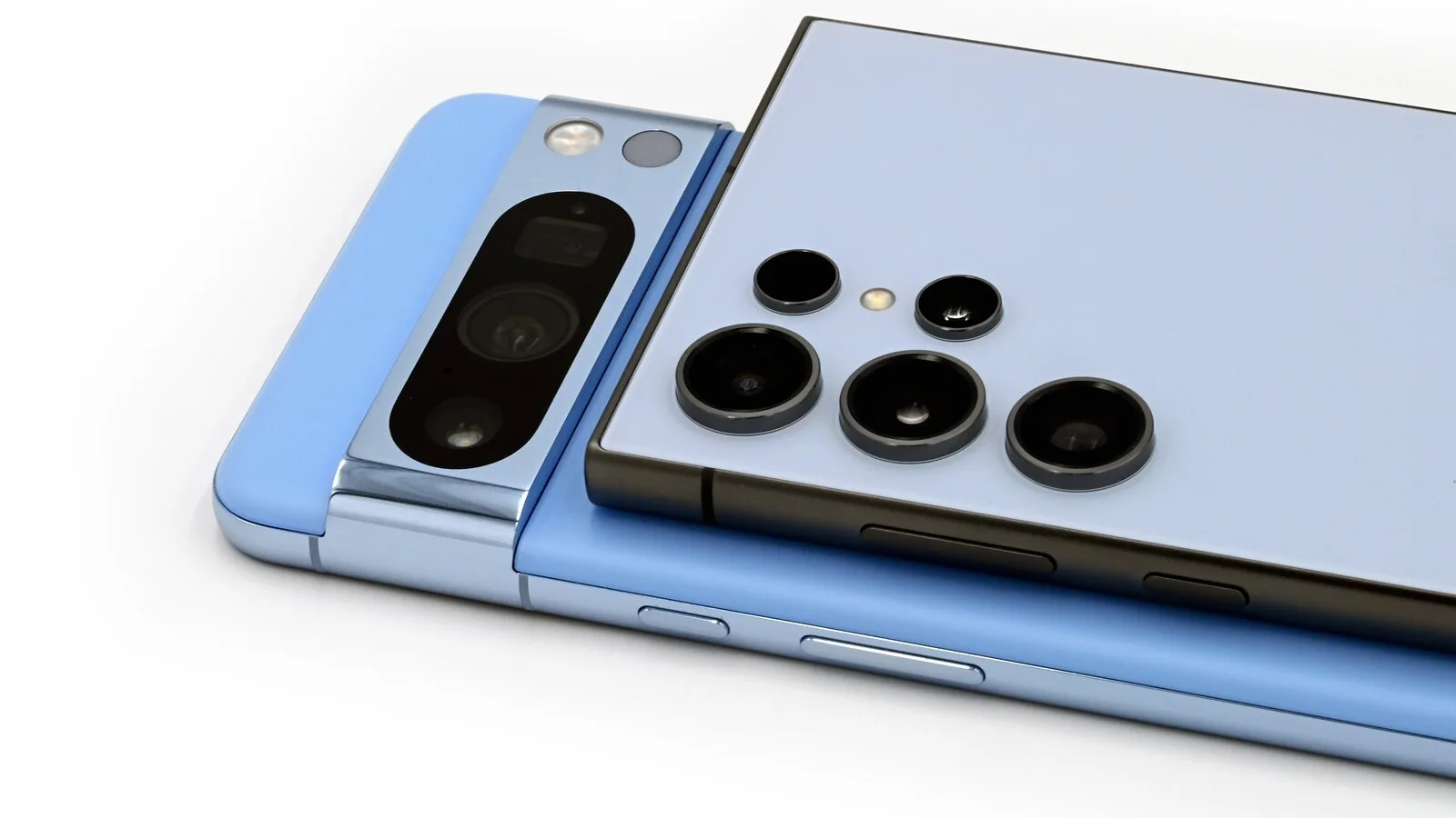 Traseira de um Google Pixel 8 Pro azul por baixo de um Samsung Galaxy S24 Ultra azul-claro, com as câmaras em destaque, sobre fundo branco