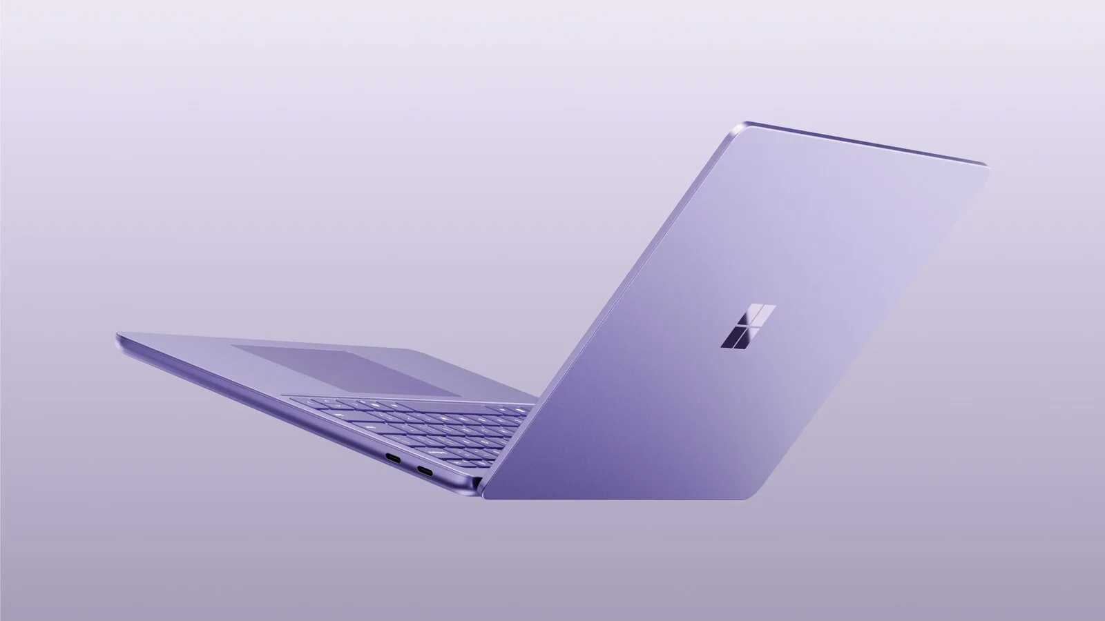 Portátil Surface Laptop de 13 polegadas em lilás, semiaberto e visto de trás, sobre um fundo da mesma cor