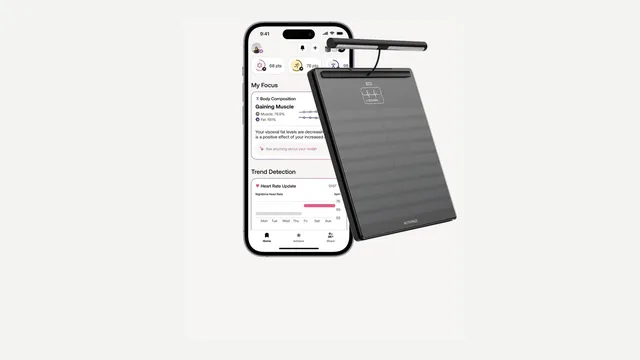 Telemóvel com a app Withings aberta num resumo de composição corporal e ritmo cardíaco, ao lado de uma balança Withings Body Scan preta com pega
