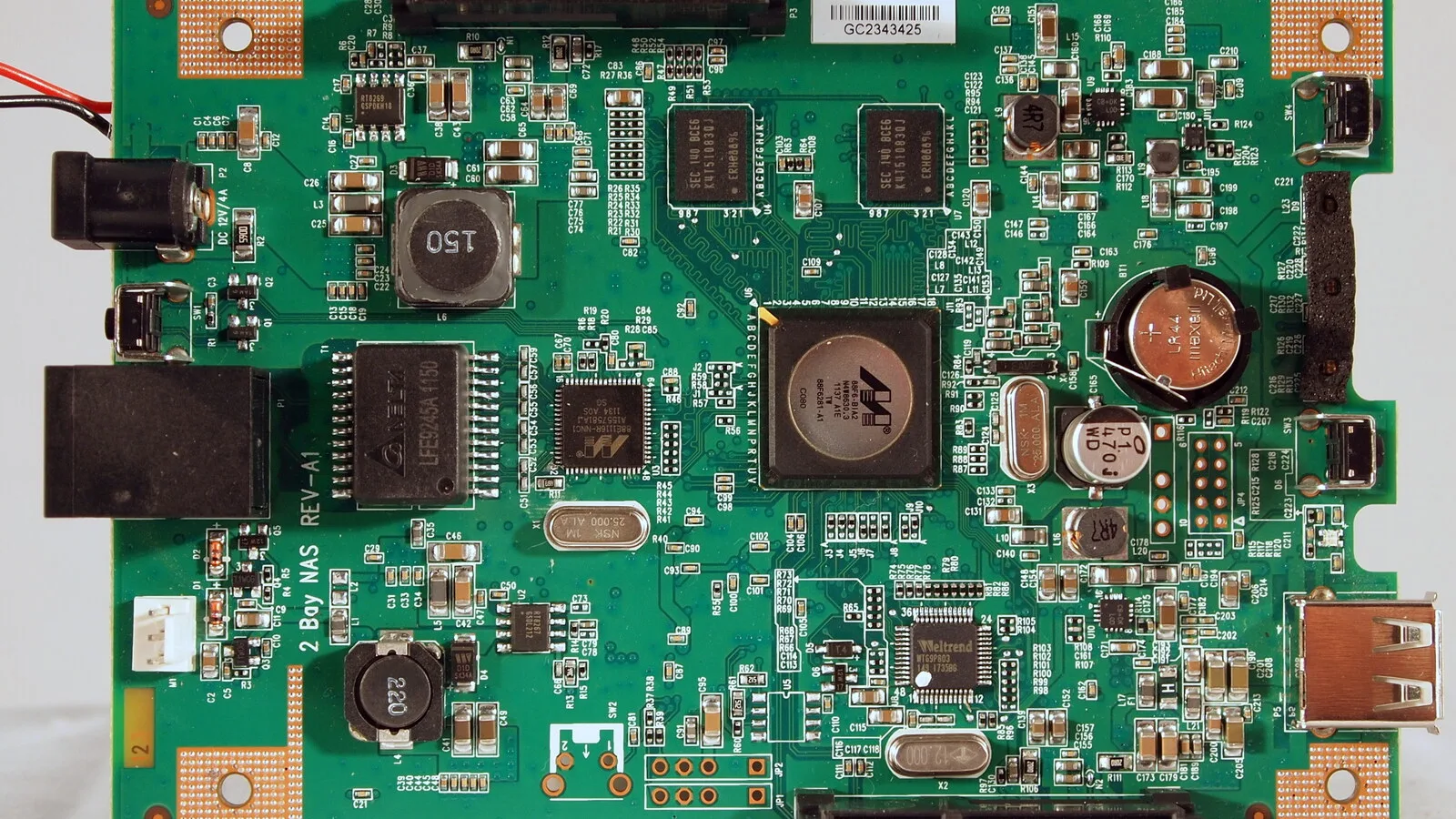 Placa de circuito verde de um disco de rede D-Link, com processador, chips de memória, pilha de botão e portas de rede e USB