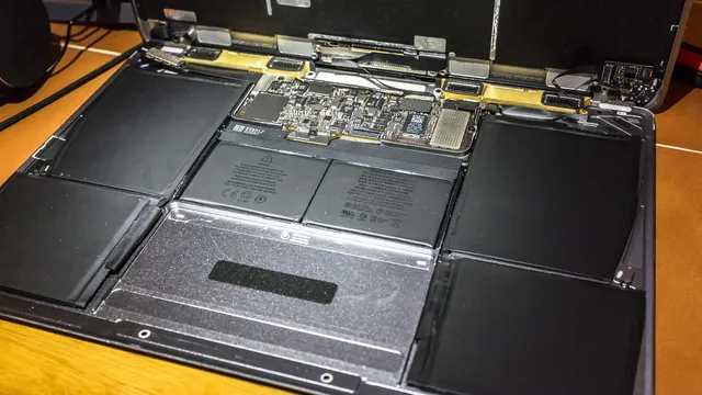 MacBook de 12 polegadas aberto por dentro, com a placa principal ao centro e as células da bateria a ocupar quase todo o espaço
