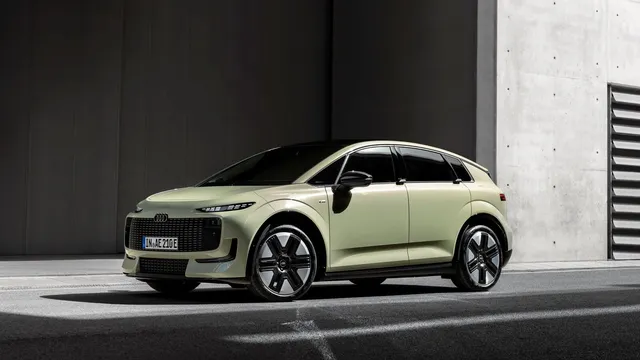 Audi A2 e-tron em verde claro, visto de frente e de lado, estacionado diante de um edifício de betão