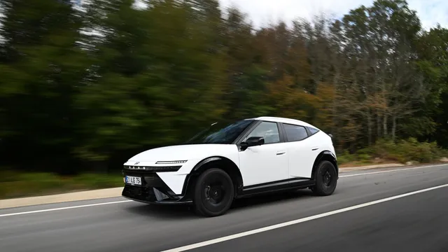 Hyundai Ioniq 3 branco com tejadilho preto a circular numa estrada ladeada de árvores, com o fundo desfocado pelo movimento