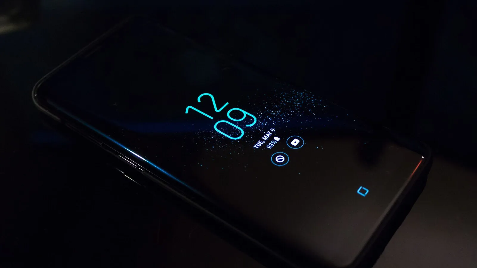 Telemóvel Android pousado numa superfície escura, com as horas e os ícones de notificação acesos no ecrã