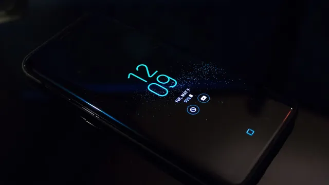 Telemóvel Android pousado numa superfície escura, com as horas e os ícones de notificação acesos no ecrã