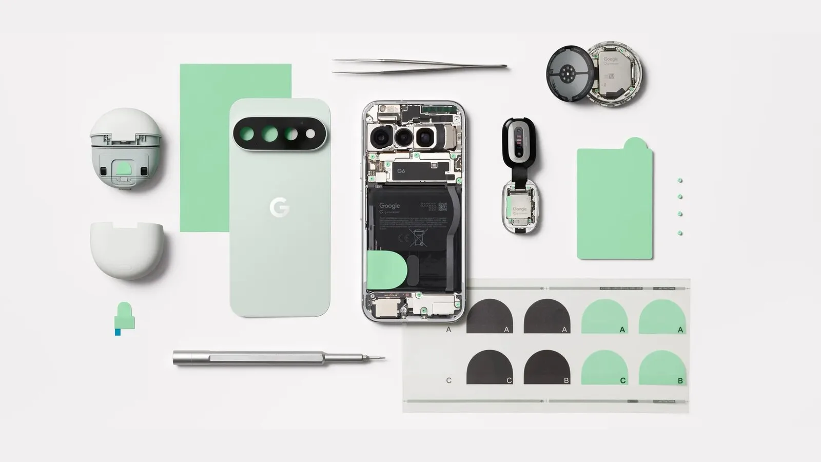 Peças de um telemóvel Pixel desmontado dispostas sobre fundo claro: tampa traseira verde, telemóvel aberto com a bateria à vista, chave de fendas, pinça, autocolantes e a caixa de uns auriculares