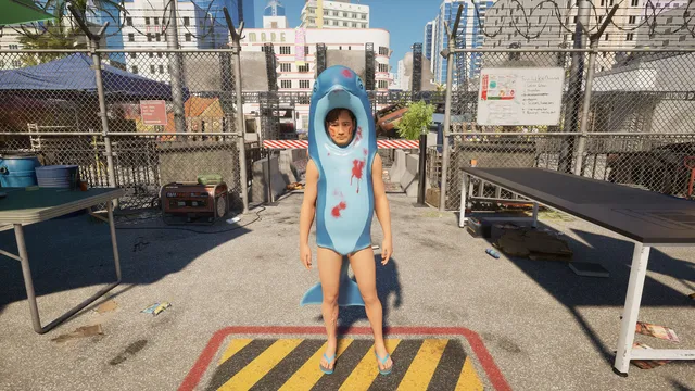 Sobrevivente vestida com um fato de tubarão azul manchado de sangue, num posto de controlo ao ar livre, com vedação de arame farpado e prédios e palmeiras ao fundo