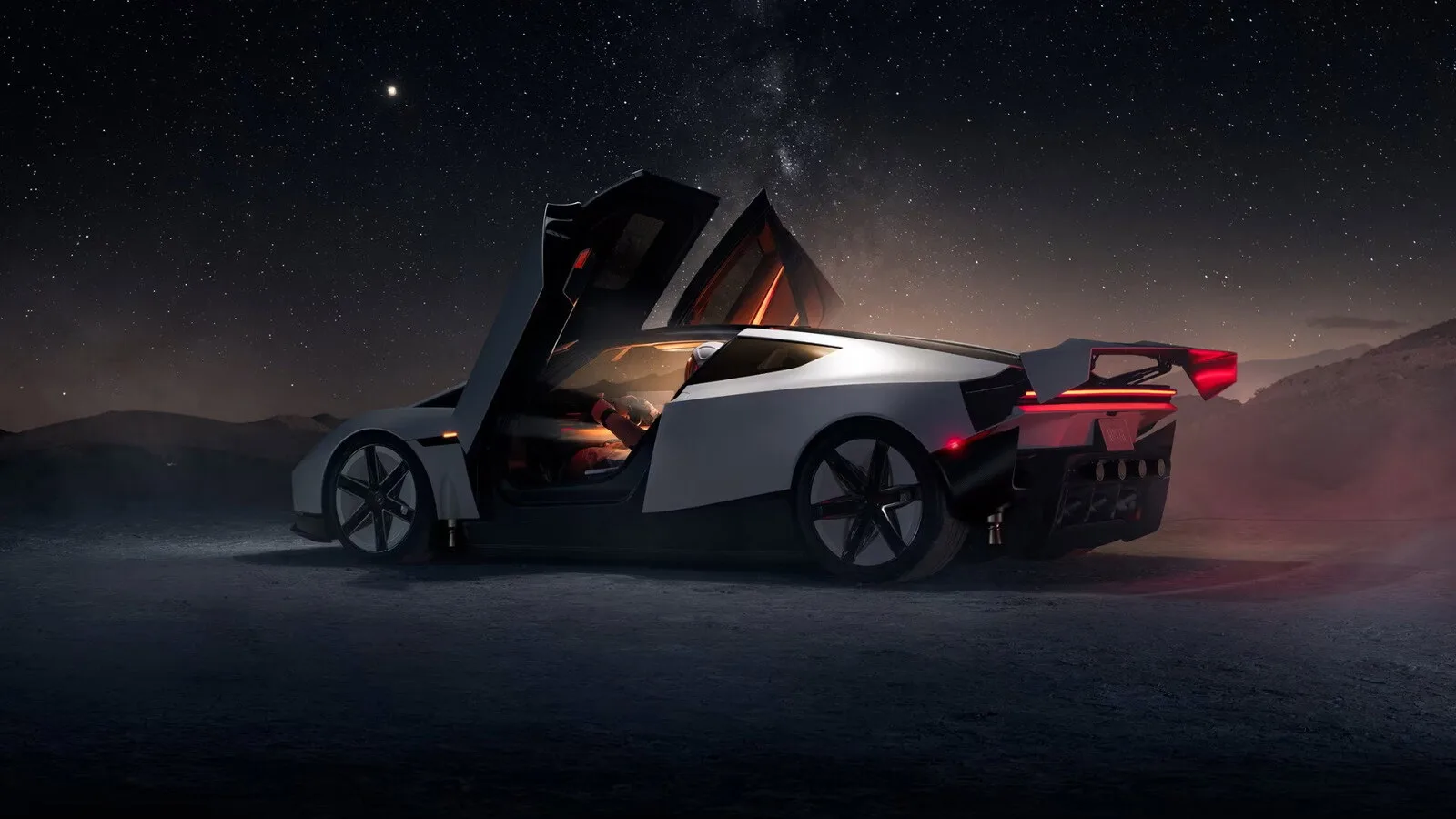 Novo Tesla Roadster branco visto de trás, com as portas abertas para cima e a asa traseira levantada, num cenário noturno de deserto