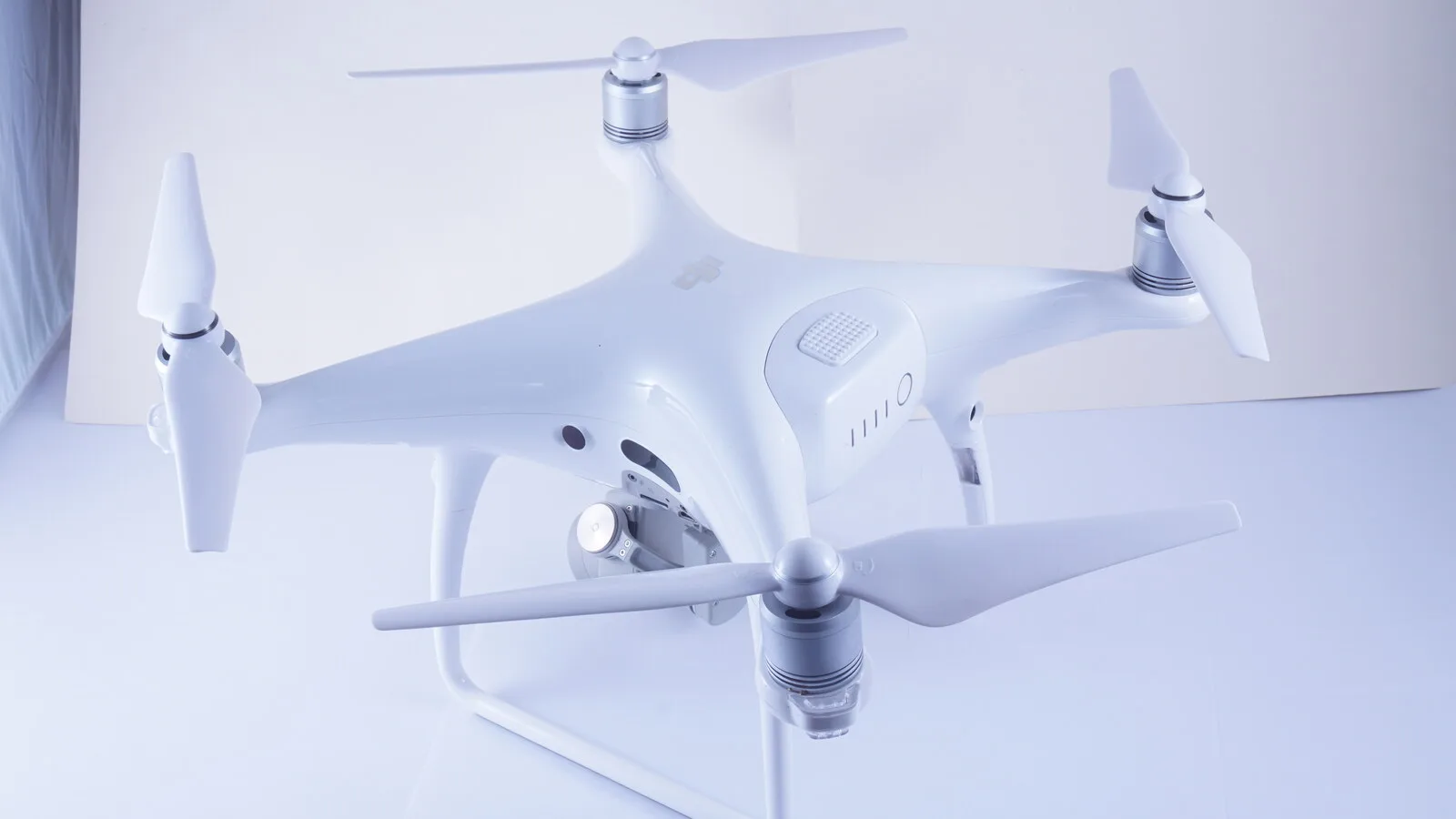 Drone DJI Phantom 4 Pro branco pousado sobre fundo claro, com as quatro hélices e a câmara suspensa por baixo do corpo