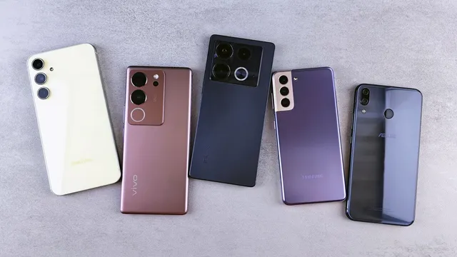 Cinco telemóveis de marcas diferentes, de costas e lado a lado sobre uma superfície cinzenta, com as câmaras traseiras à vista