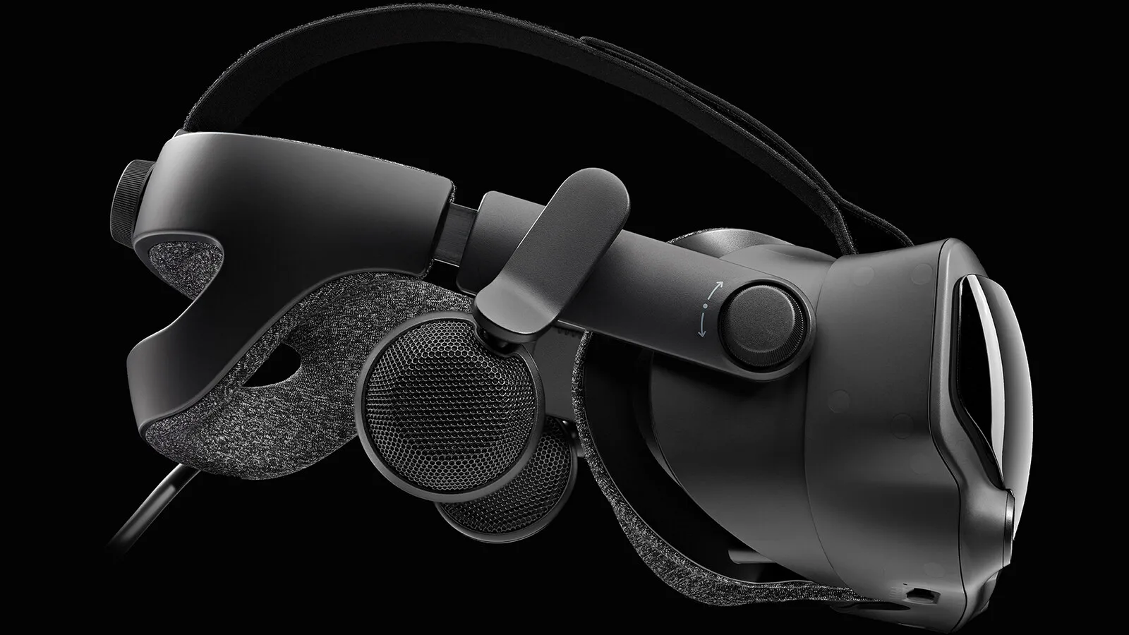Óculo de realidade virtual Valve Index preto visto de lado sobre fundo escuro, com a fita de cabeça em tecido cinzento, os altifalantes afastados da cabeça e o cabo de ligação