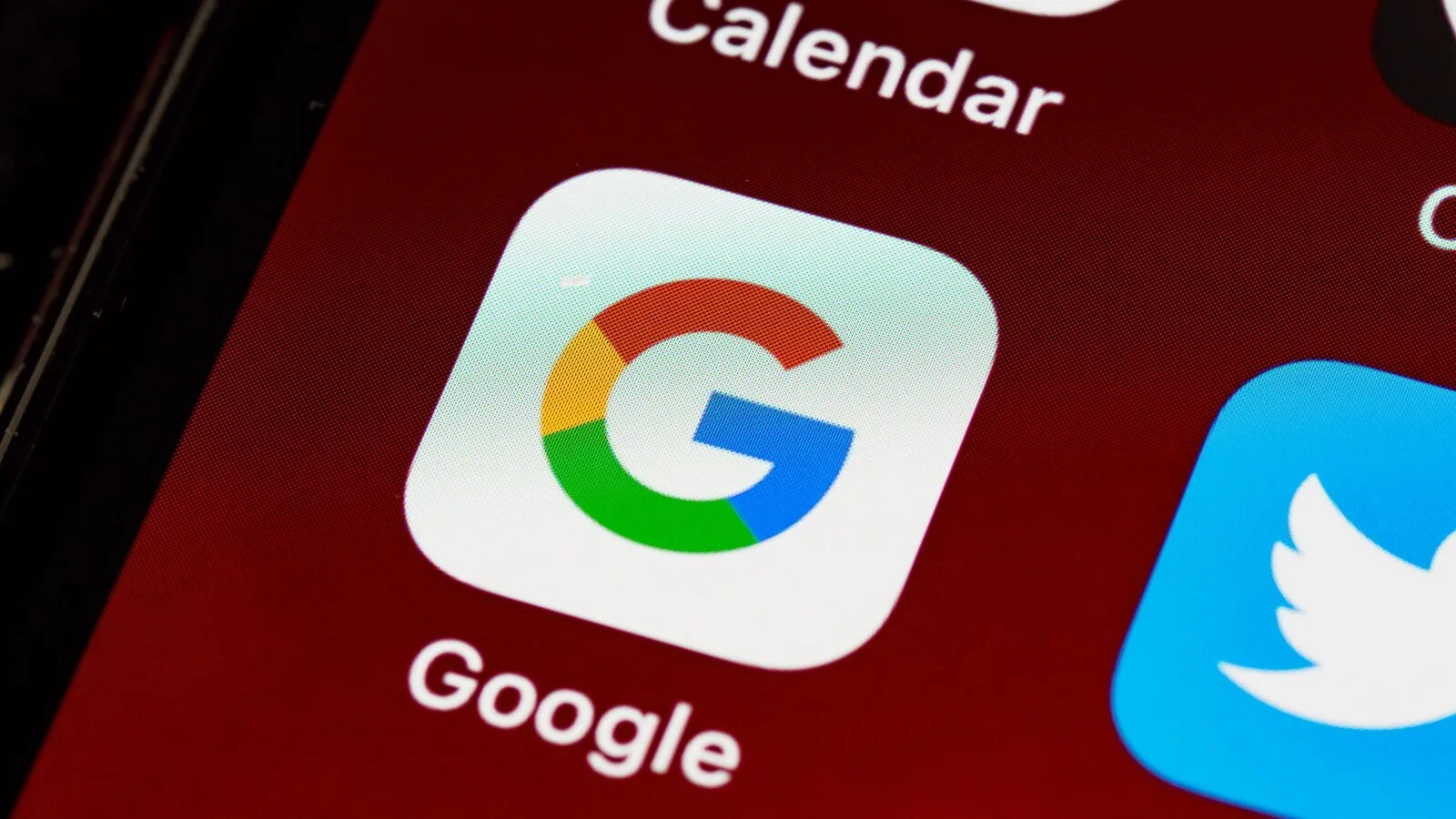 Ecrã de telemóvel visto de perto com o ícone da app Google em destaque, entre os ícones do calendário e do Twitter