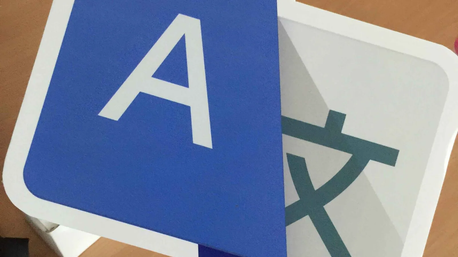 Placa em cartão com o ícone do Google Tradutor, com a letra A sobre fundo azul e um carácter oriental sobre fundo cinzento