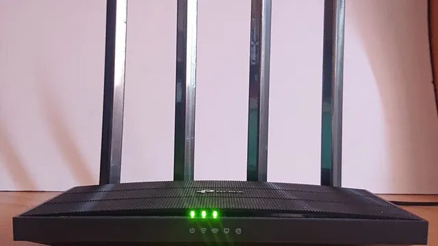 Router Wi-Fi preto com quatro antenas e luzes verdes acesas, pousado numa mesa de madeira