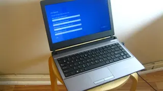 Portátil pousado num banco de madeira com o ecrã de configuração inicial do Windows