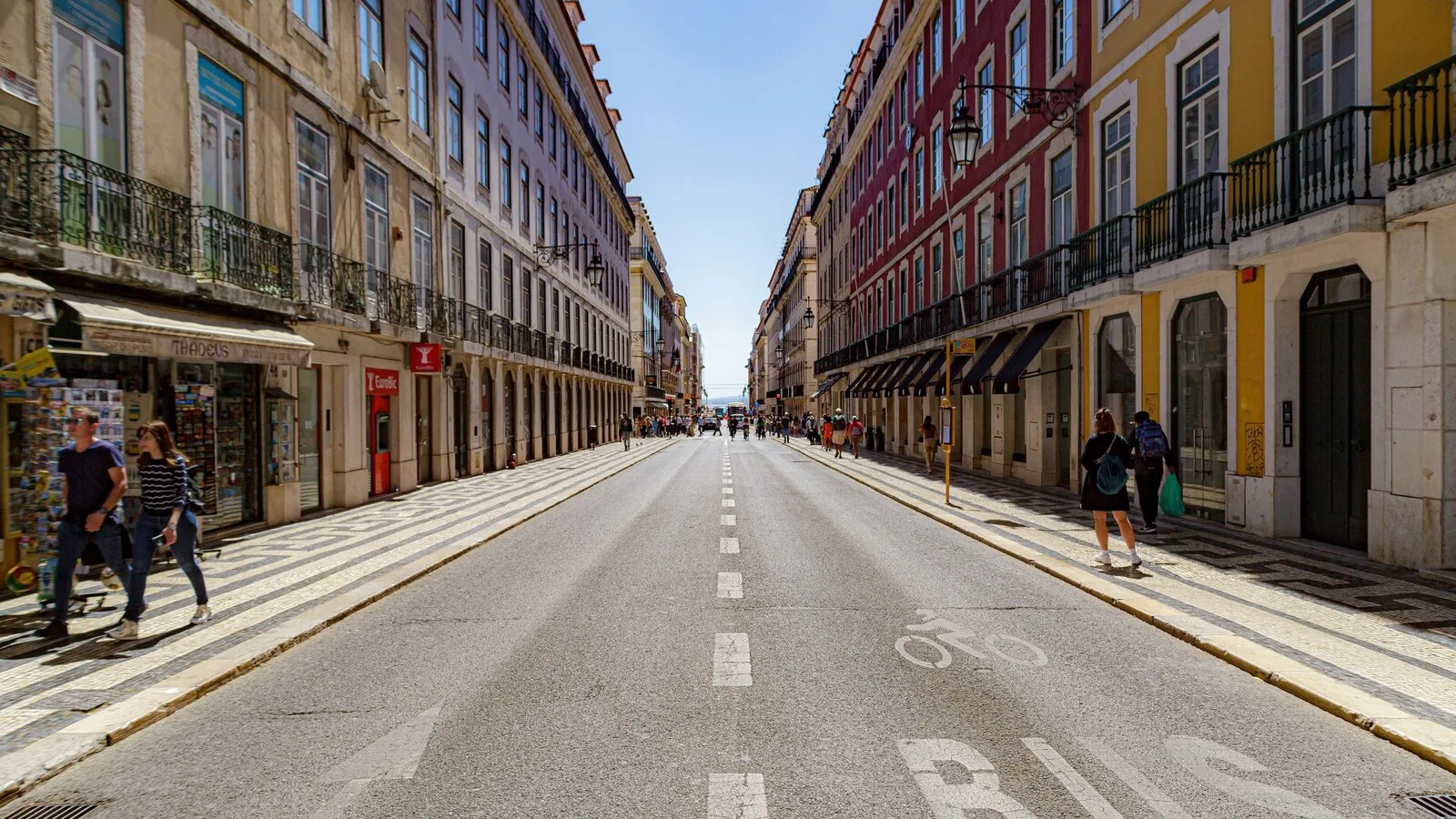 Rua de Lisboa com faixa de autocarro pintada no asfalto, entre prédios coloridos