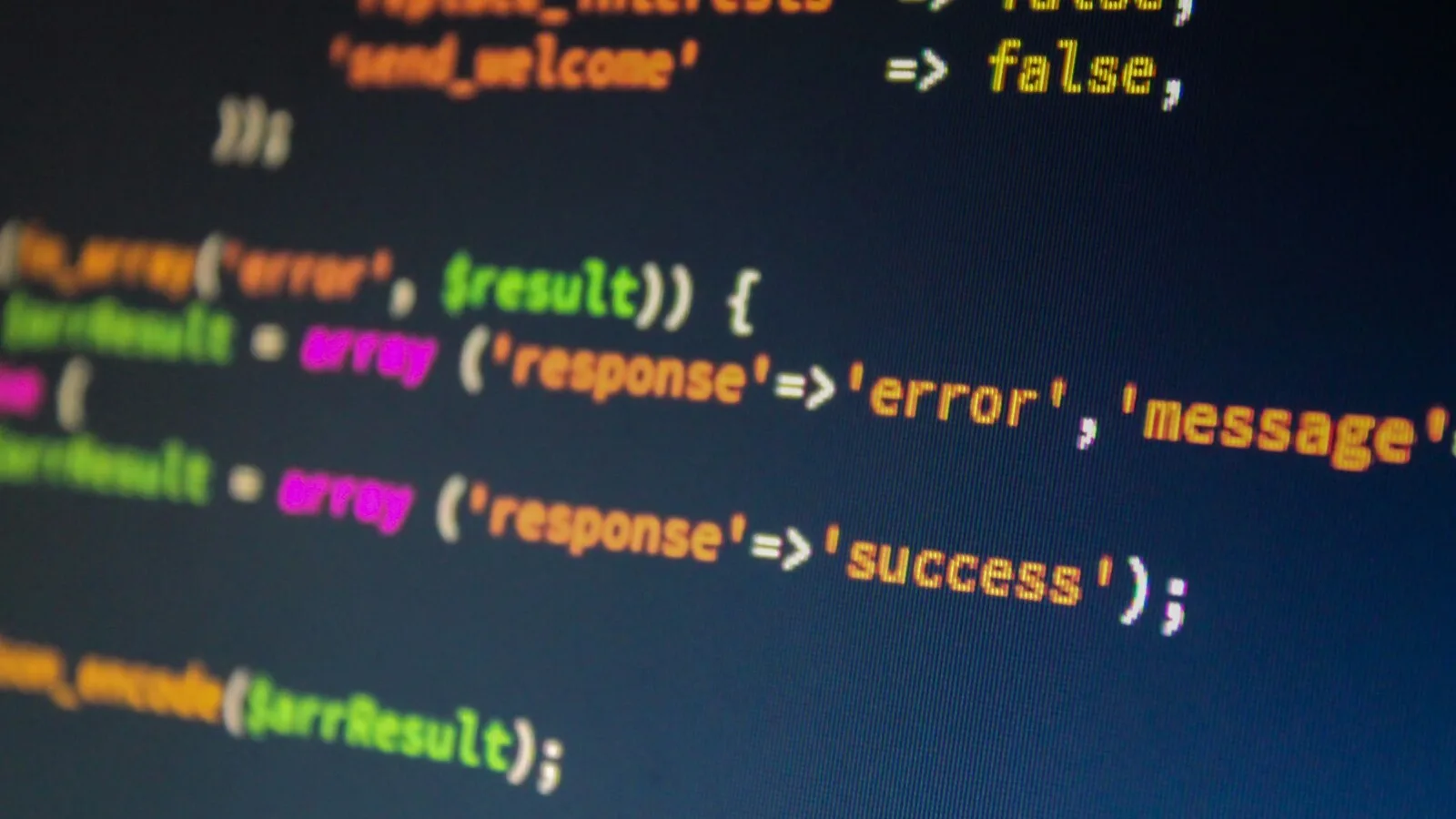 Grande plano de um monitor com linhas de código PHP coloridas sobre fundo azul escuro, parcialmente desfocadas