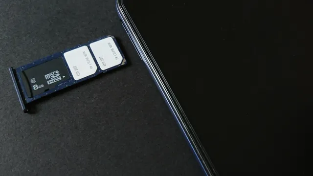 Gaveta de cartões de um telemóvel retirada, com dois cartões SIM e um cartão de memória, pousada junto ao aparelho sobre uma superfície escura