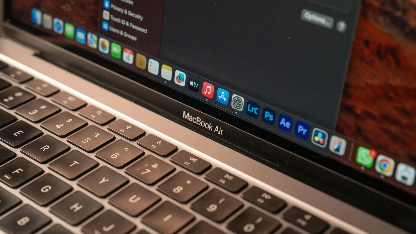 Grande plano do teclado de um MacBook Air prateado, com a barra de aplicações do macOS visível no ecrã