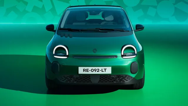 Renault Twingo E-Tech elétrico verde visto de frente, com faróis redondos acesos, num estúdio de fundo verde