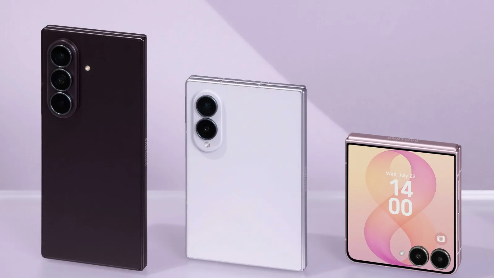 Três telemóveis dobráveis Samsung sobre fundo lilás: o Galaxy Z Fold8 Ultra escuro e o Fold8 branco, fechados e vistos de trás, e um Z Flip8 rosa fechado com o relógio no ecrã exterior