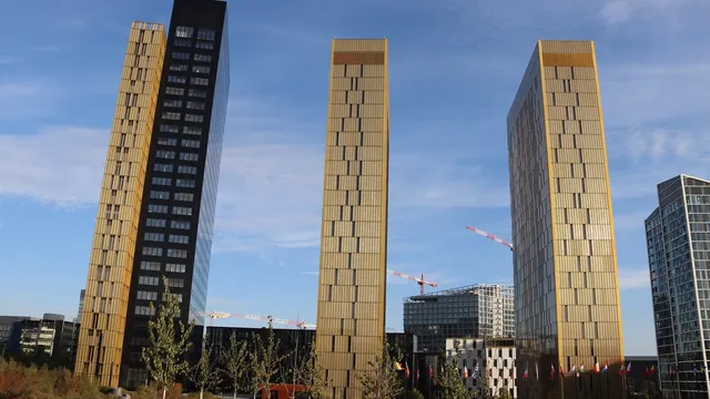 Três torres douradas do complexo do Tribunal de Justiça da União Europeia, no Luxemburgo, contra um céu azul com gruas ao fundo