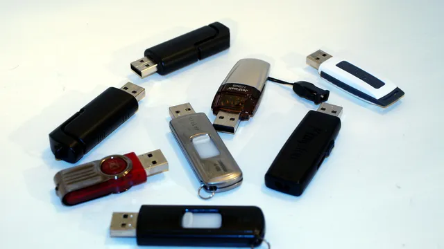 Oito pens USB de várias marcas e cores espalhadas sobre uma superfície branca