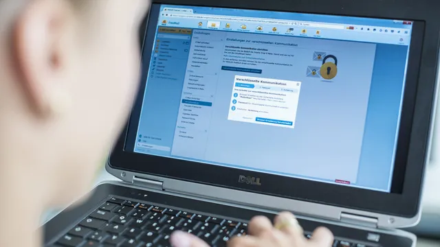 Pessoa de costas a escrever num portátil Dell com uma página de configuração de comunicação cifrada aberta no ecrã e o desenho de um cadeado