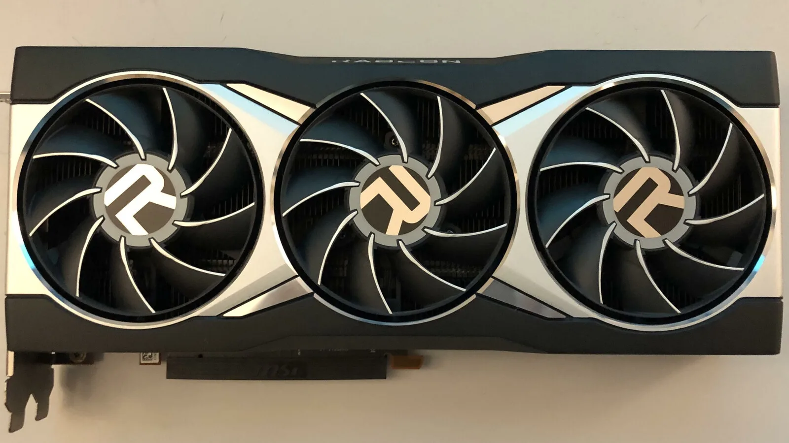 Placa gráfica AMD Radeon RX 6900 XT vista de cima, com três ventoinhas pretas e prateadas e o logótipo R no centro de cada uma
