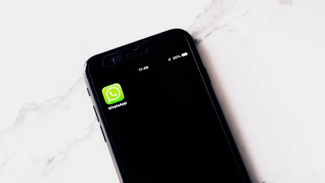 Telemóvel pousado numa superfície de mármore com o ícone do WhatsApp no ecrã