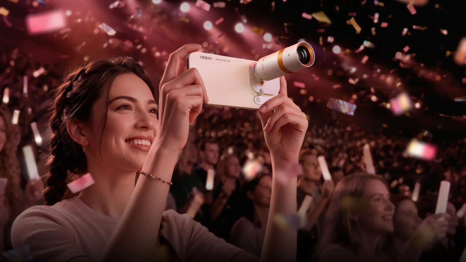 Mulher num concerto, rodeada de confetis, a fotografar com um telemóvel OPPO branco com uma lente teleconversora prateada e laranja encaixada na câmara