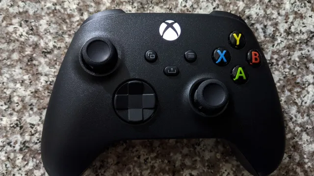 Comando preto da Xbox Series pousado sobre uma bancada de granito, com os botões coloridos X, Y, A e B