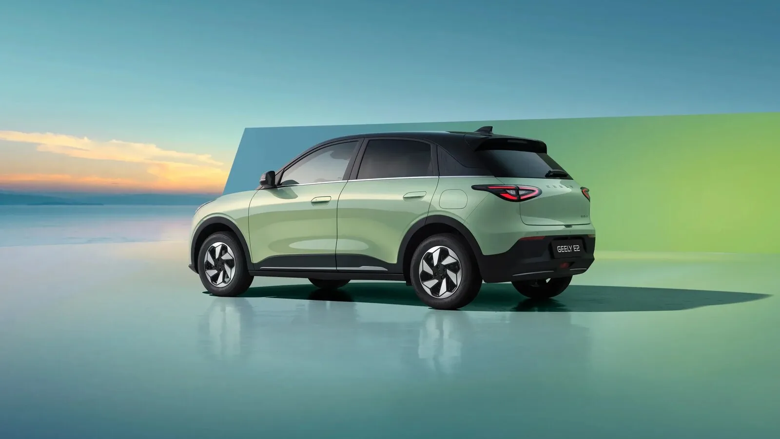Geely E2 verde-claro visto de trás e de lado, num cenário de estúdio com mar ao fundo