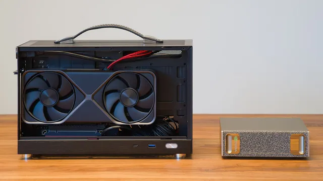 Computador compacto aberto com uma placa gráfica GeForce RTX 5070 Founders Edition à vista, ao lado de um pequeno computador NVIDIA DGX Spark, sobre uma mesa de madeira