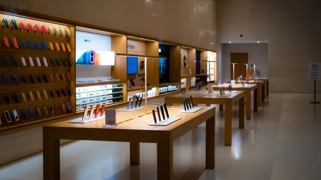 Interior de uma loja de tecnologia com telemóveis expostos em mesas de madeira e capas na parede