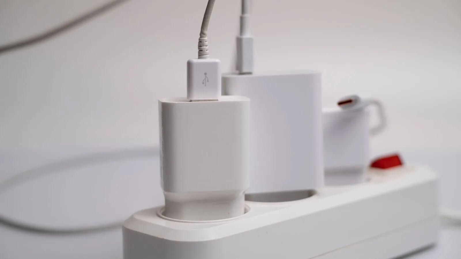 Carregadores brancos ligados a uma extensão elétrica, com cabos USB e USB-C
