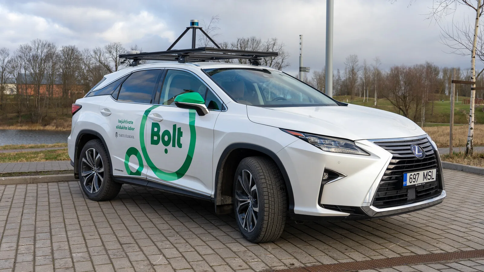 SUV branco com as cores da Bolt e sensores montados numa estrutura no tejadilho, estacionado num parque com árvores