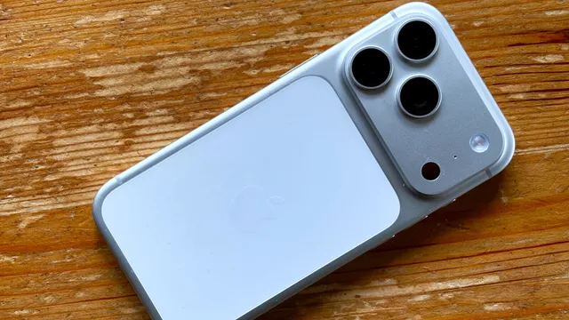 iPhone 17 Pro prateado visto de trás, pousado numa mesa de madeira, com três câmaras no canto superior