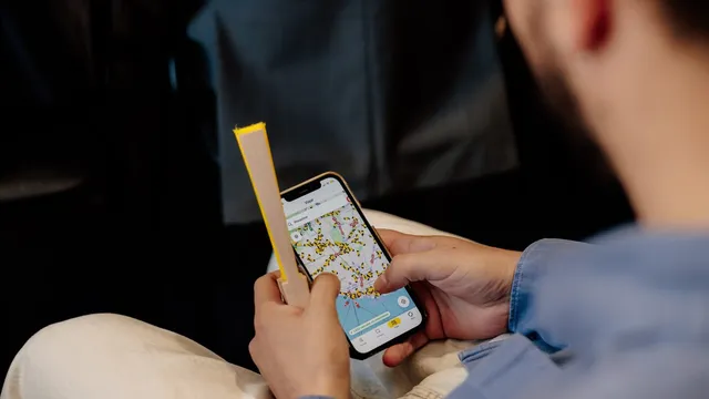 Pessoa segura um telemóvel com a app navegante aberta no separador Viajar, com um mapa de Lisboa cheio de ícones de autocarros