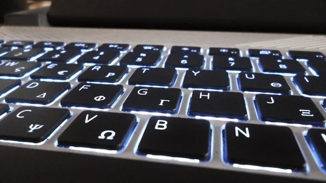 Teclado de portátil iluminado por trás, visto de perto e de lado, com teclas latinas e gregas