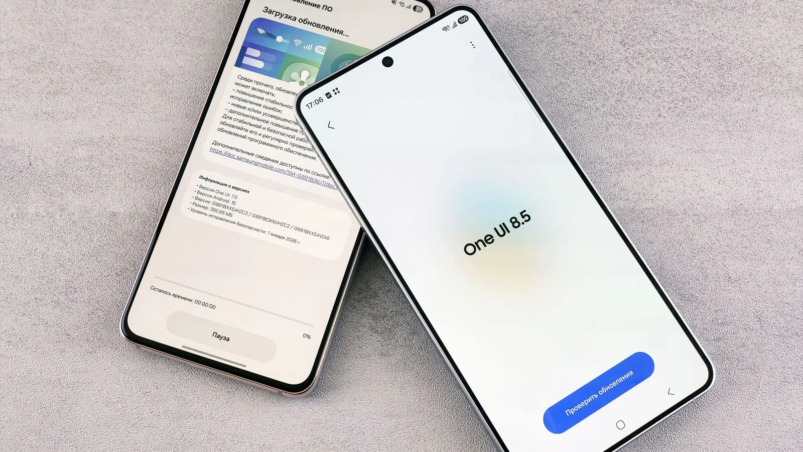 Dois telemóveis Samsung sobre uma mesa cinzenta, um a descarregar uma atualização e outro com o ecrã da One UI 8.5