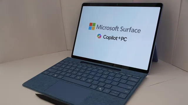 Tablet Microsoft Surface com teclado azul e caneta preta, com o ecrã a mostrar as palavras Microsoft Surface e Copilot+ PC