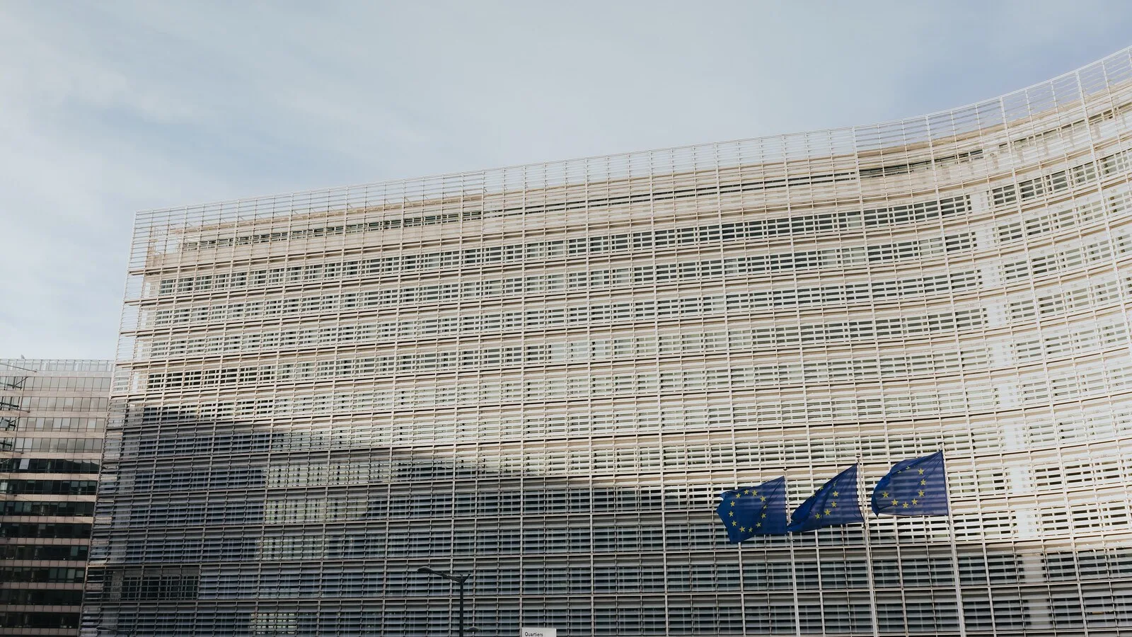 Fachada do edifício Berlaymont, sede da Comissão Europeia em Bruxelas, com três bandeiras da União Europeia