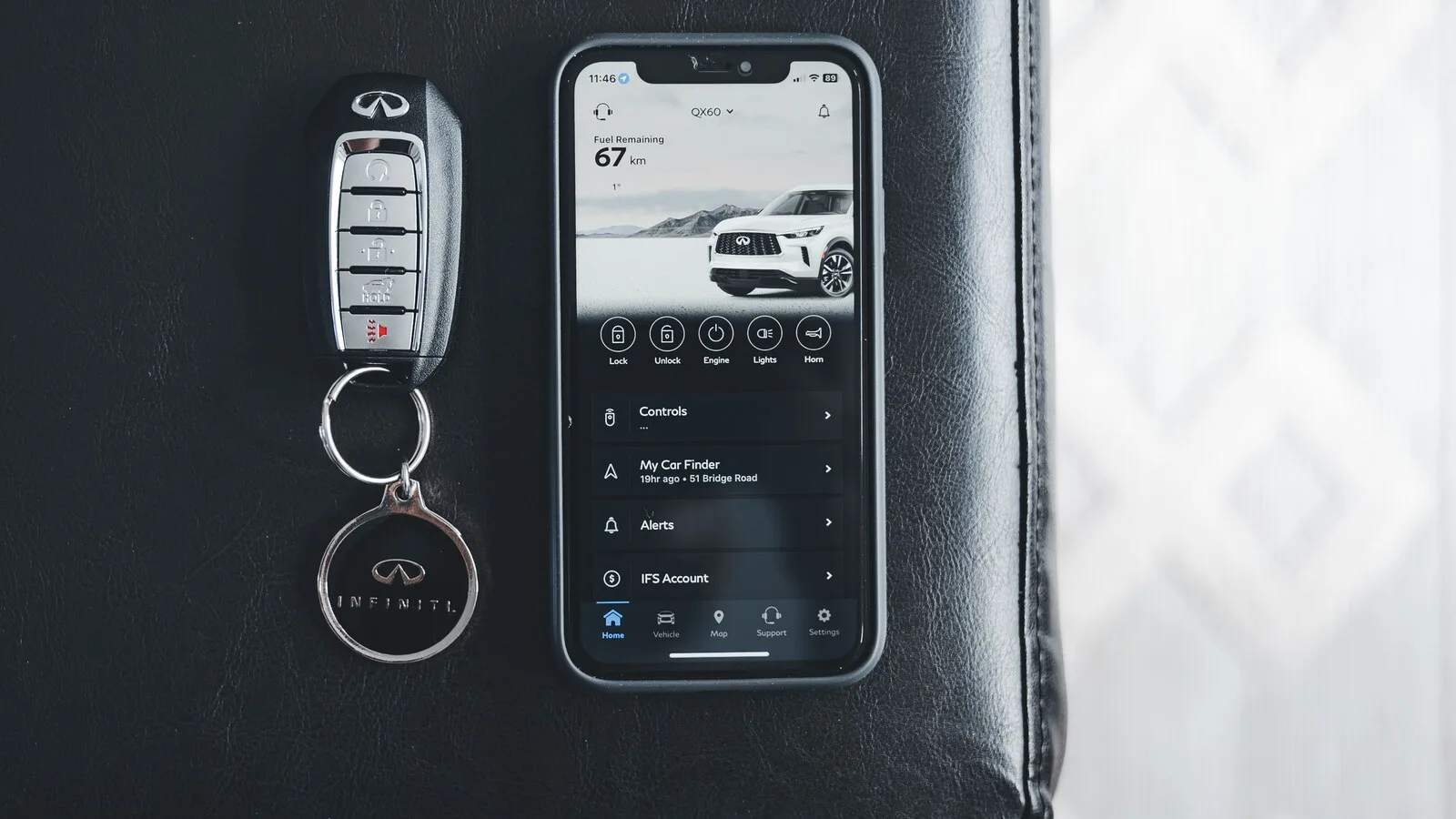 Comando de chave de um Infiniti ao lado de um telemóvel com a app da marca aberta, com botões para trancar, destrancar e ligar o motor