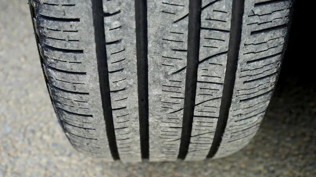 Pormenor do piso de um pneu de automóvel gasto, com quatro sulcos longitudinais e pequenas lamelas